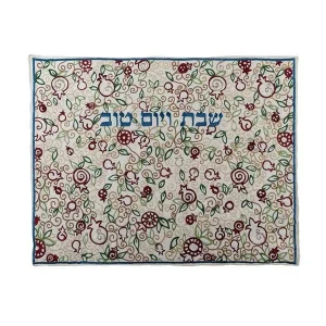 כיסוי חלה לשבת משולב בבדים ורקמות שונות בגווני אדום, ירוק וזהב על רקע שמנת, עם עיטורי רימונים ועלים וכיתוב שבת ויום טוב