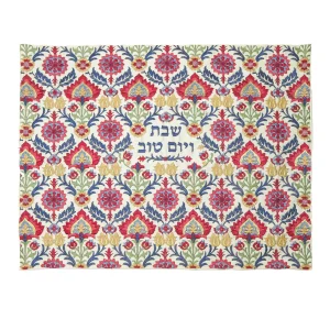 כיסוי חלה לשבת משולב בבדים ורקמות שונות בגווני אדום, כחול, ירוק וזהב על רקע שמנת, עם עיטורי פרחים ודוגמאות צמחיות וכיתוב שבת ויום טוב