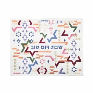 כיסוי חלה לשבת משולב בבדים ורקמות שונות בגוונים צבעוניים על רקע שמנת, עם עיטורי צורות גיאומטריות ומגיני דוד וכיתוב שבת ויום טוב