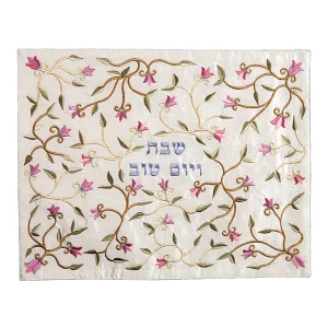 כיסוי חלה לשבת משולב בבדים ורקמות שונות בגווני ורוד, ירוק וזהב על רקע שמנת, עם עיטורי פרחים וכיתוב שבת ויום טוב