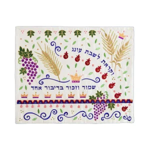 כיסוי חלה לשבת משולב בבדים ורקמות שונות בגווני זהב, סגול וכחול על רקע שמנת, עם עיטורי שיבולים, ענבים, רימונים וכתרים וכיתוב לקראת שבת עונג ושמור וזכור