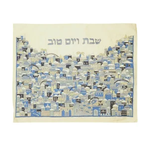 כיסוי חלה לשבת משולב בבדים ורקמות שונות בגווני כחול, תכלת ואפור על רקע שמנת, עם עיטורי נוף ירושלים וכיתוב שבת ויום טוב