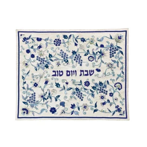 כיסוי חלה לשבת משולב בבדים ורקמות שונות בגווני כחול, תכלת וכסף על רקע שמנת, עם מסגרת כחולה, עיטורי אשכולות ענבים, פרחים ועלים וכיתוב שבת ויום טוב