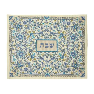 כיסוי חלה לשבת משולב בבדים ורקמות שונות בגווני כחול ותכלת על רקע שמנת, עם עיטורי פרחים ורימונים וכיתוב שבת